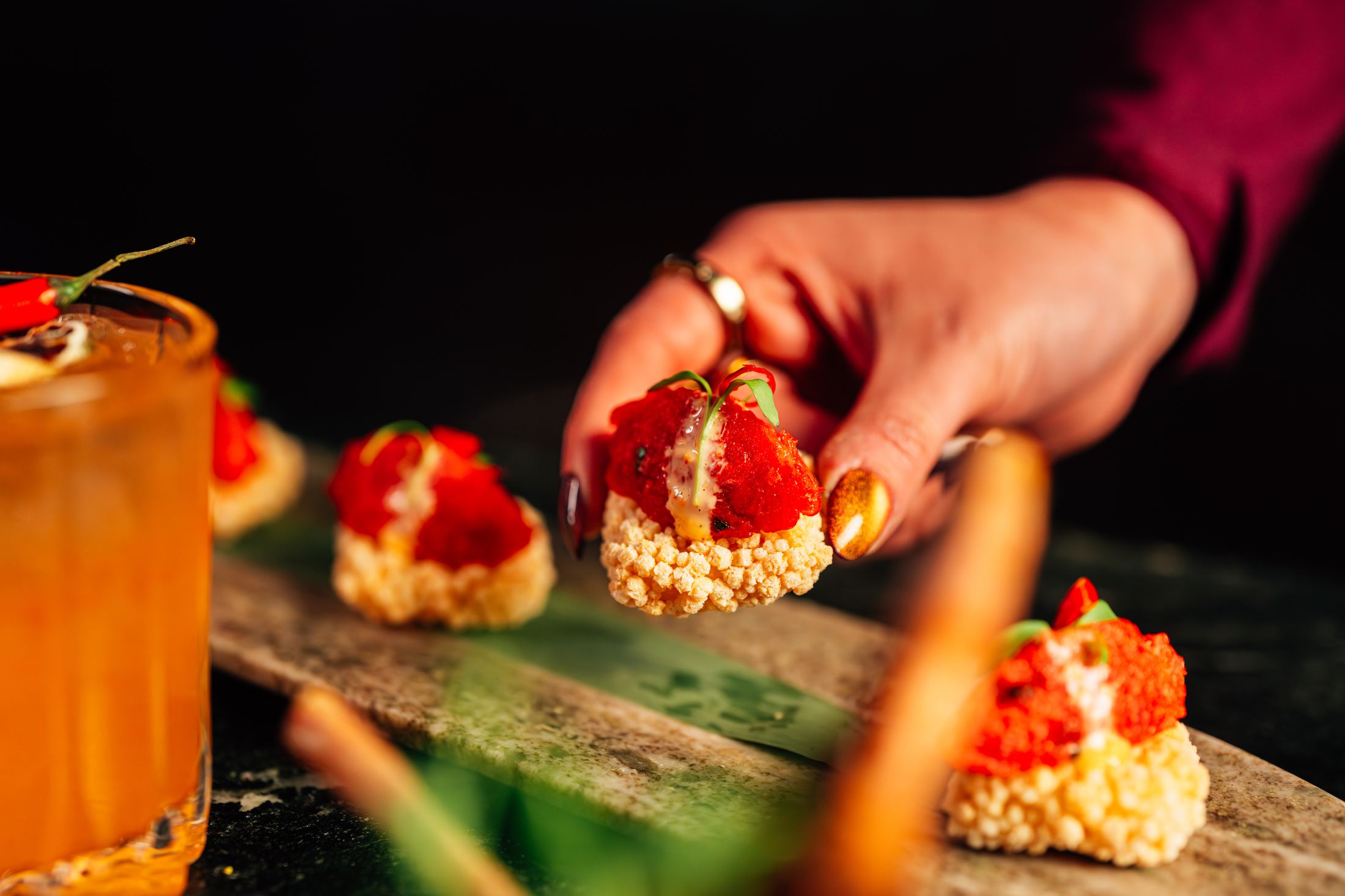 A strawberry canapé placed onto a crisped rice base